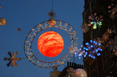 Low angle view of illuminated lanterns hanging against sky