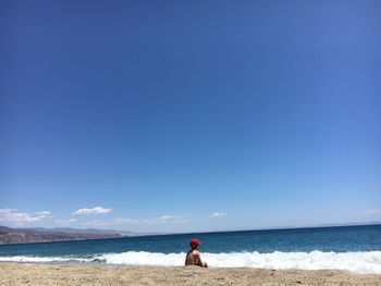 Man on beach against blue sky