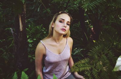 Portrait of young woman against plants