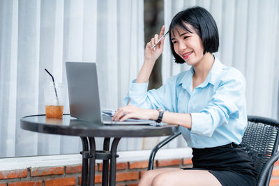 Young woman using mobile phone while sitting at home