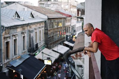 Side view of man standing at balcony in city