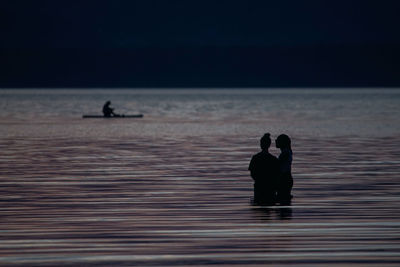 Silhouette people at beach against sky during sunset