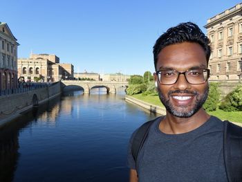 Portrait of smiling mid adult man over river in city