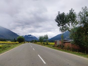 Road by trees against sky