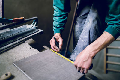 Cropped image of male worker measuring wood at table