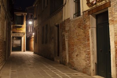 Empty alley amidst buildings at night