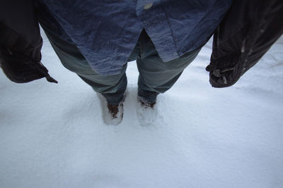 Low section of person standing on snow covered land