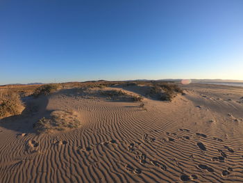 Scenic view of desert against clear blue sky