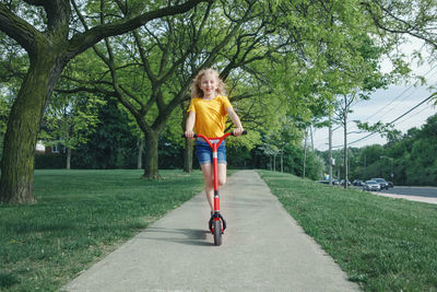 Cute girl riding on push scooter at park