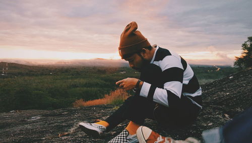 Side view of man on field against sky during sunset