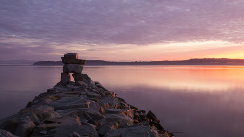 Rear view of man standing on rock by sea against sky