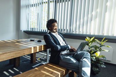 Smiling businessman working on laptop at workplace