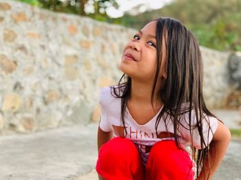 Portrait of smiling girl crouching against wall