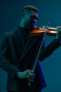 Midsection of man playing violin against black background