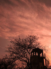 Low angle view of silhouette tree and building against sky at sunset
