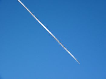 Low angle view of vapor trail against clear blue sky