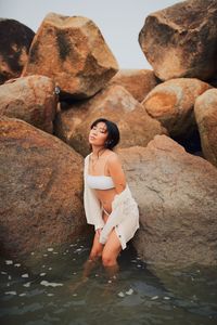 Thoughtful young woman in sea against rocks