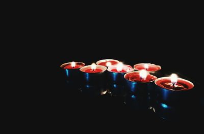 Close-up of illuminated candles over black background