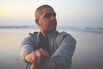 Thoughtful man standing at beach during sunset