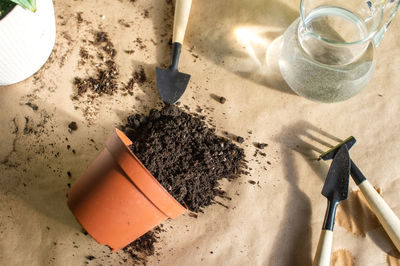 A pot of soil lies on a table with a tool for home plants. scatter the soil