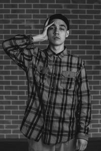 Portrait of young man standing against wall