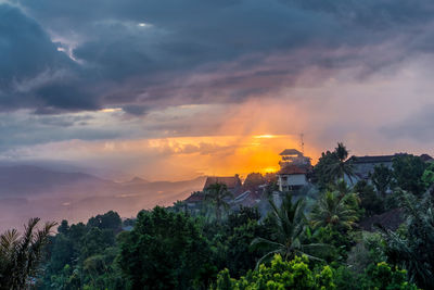 Scenic view of trees and buildings against sky during sunset