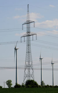 Wind turbines and electricity pylon against sky