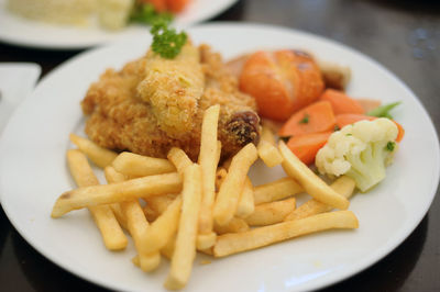 Chicken chop with french fries served in plate on table at restaurant