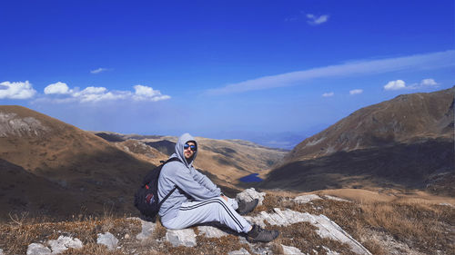 Man sitting on rock against mountains