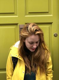 Portrait of smiling young woman against yellow door