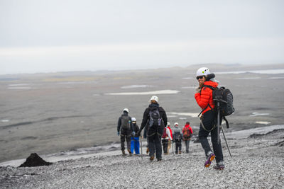 Rear view of people walking on snow covered land