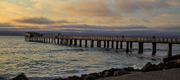 Pier over sea against sky during sunset