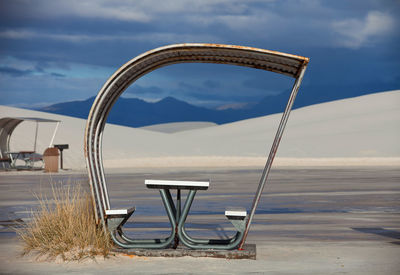 Deck chairs on beach against sky