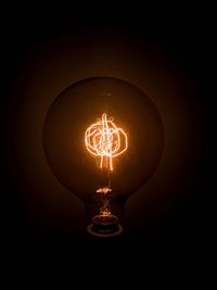 Low angle view of illuminated light bulb in darkroom