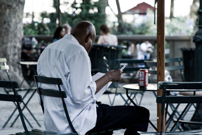 Man reading paper at sidewalk cafe