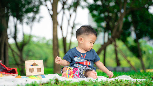 Cute boy playing with toy sitting outdoors