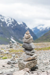 Stack of stones on rock against sky and mountains 