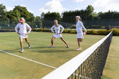 Mature women doing stretching exercises before playing tennis