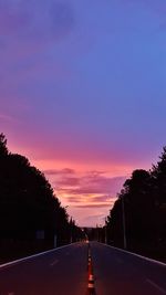 Road amidst silhouette trees against sky during sunset