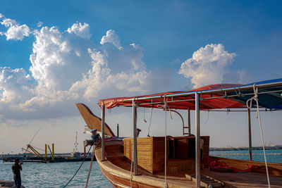 Boat moored on pier by sea against sky