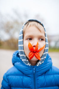 Portrait of boy with orange flower in his mouth 