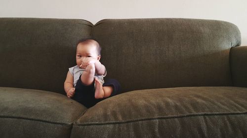 Portrait of cute boy sitting on sofa at home