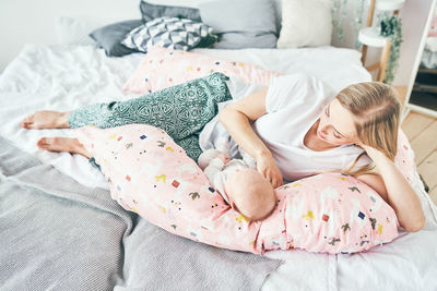 Full length of mother with daughter lying down on bed at home