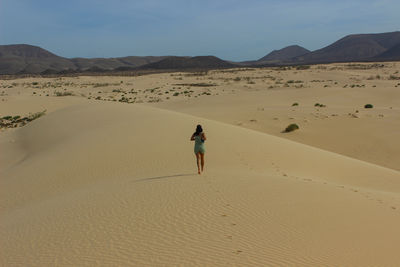 Rear view of man walking at desert