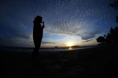 Silhouette of people on beach at sunset