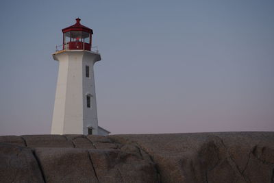 Lighthouse by sea against clear sky