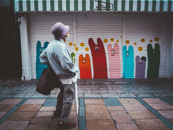 Rear view of man walking on footpath against building