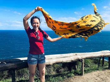 Portrait of smiling woman standing against sea