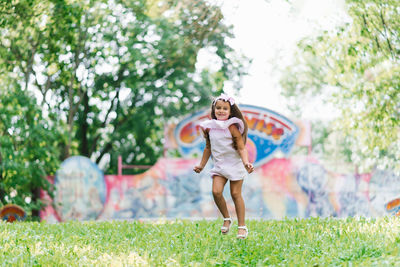 Cute little girl in the park jumps up on the grass and smiles