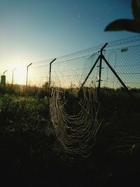 Silhouette fishing net on field against sky at sunset